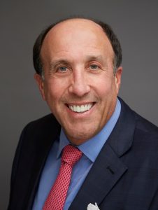 A man in a suit and tie smiling for the camera.