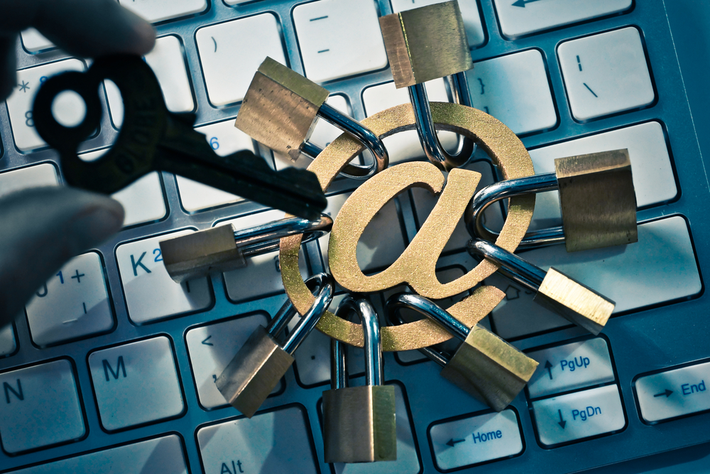 a key pointing at an at sign with locks on it over a computer keyboard